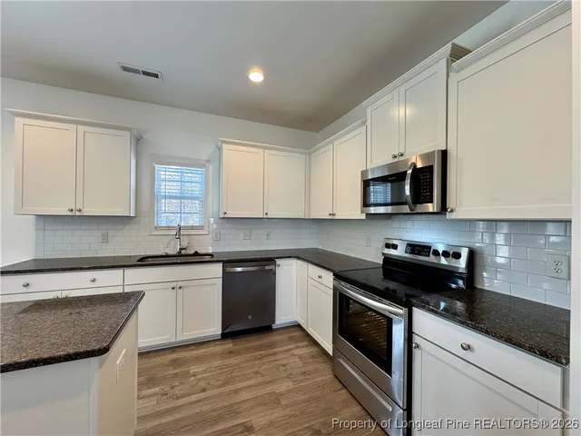 a kitchen with stainless steel appliances granite countertop white cabinets granite counter tops and a window