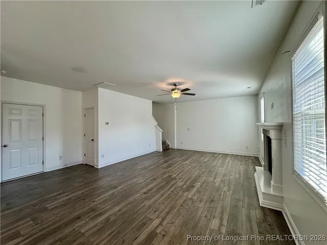 an empty room with wooden floor chandelier fan and windows