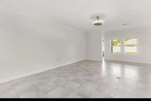 an empty room with windows and ceiling fan