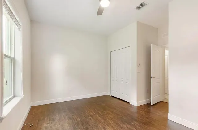 an empty room with wooden floor and windows