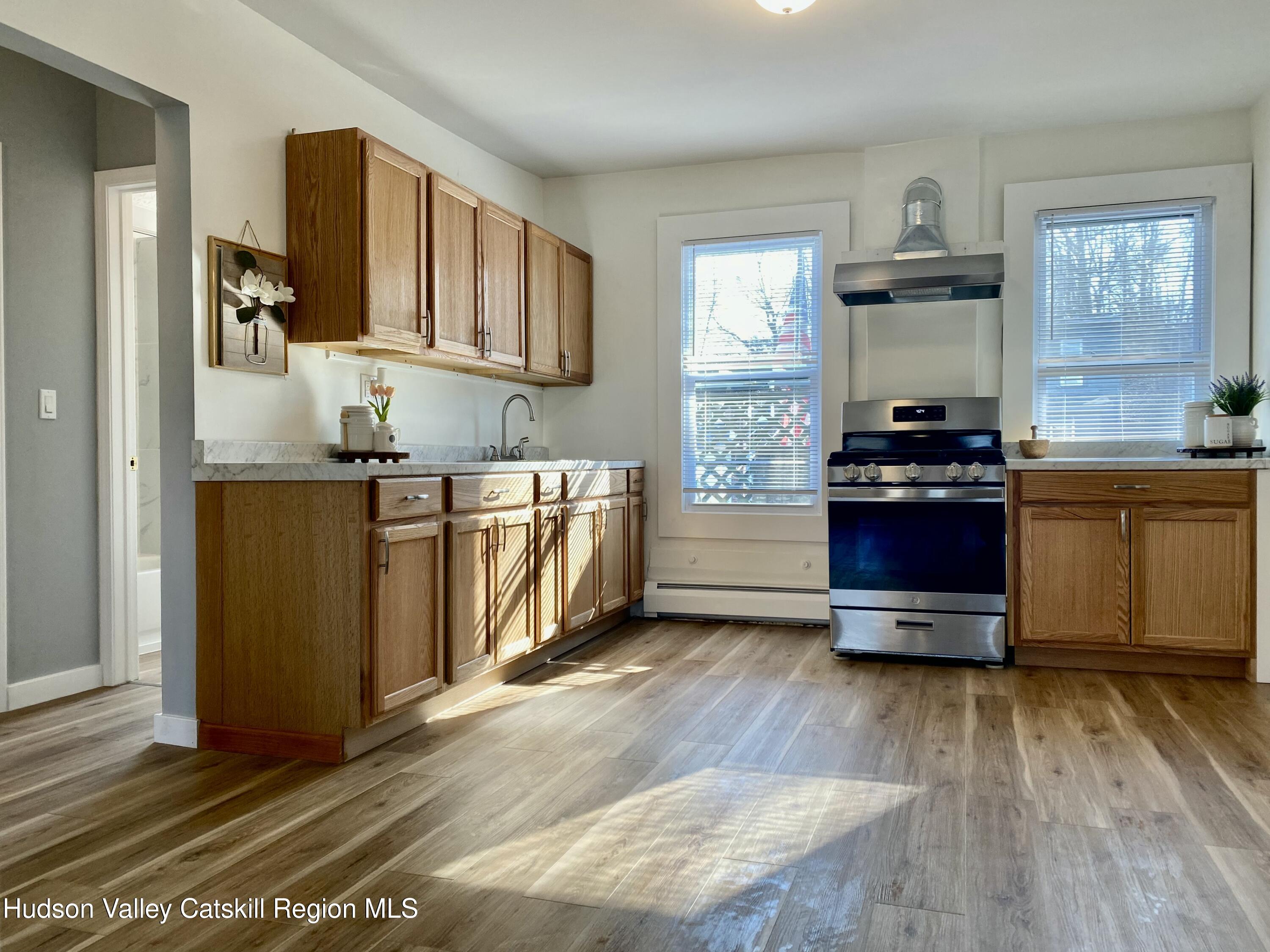 91 Broadway, Unit #2 Kingston, NY 12401 - Photo 3 of 14 a kitchen with stainless steel appliances a stove and wooden floor