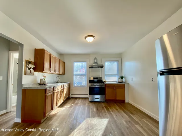 a kitchen with stainless steel appliances kitchen island granite countertop a refrigerator a stove and a wooden floors