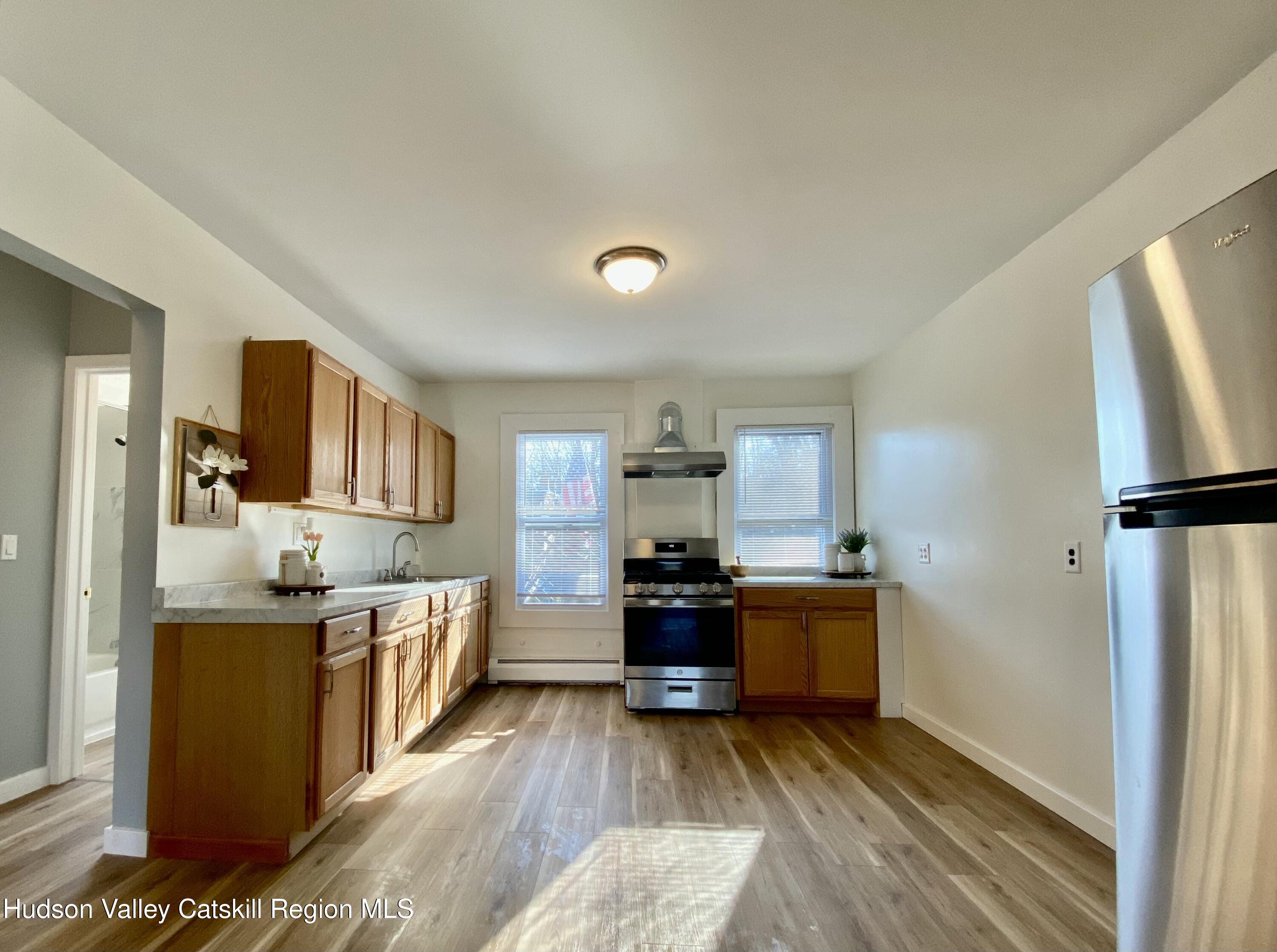 91 Broadway, Unit #2 Kingston, NY 12401 - Photo 5 of 14 a kitchen with stainless steel appliances kitchen island granite countertop a refrigerator a stove and a wooden floors