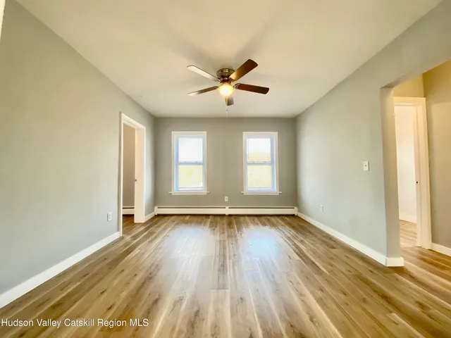 a view of an empty room with window and wooden floor