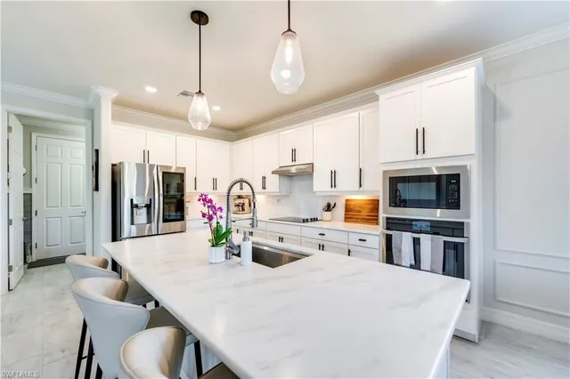 a large kitchen with stainless steel appliances granite countertop a stove a refrigerator a oven a sink with a dining table and chairs