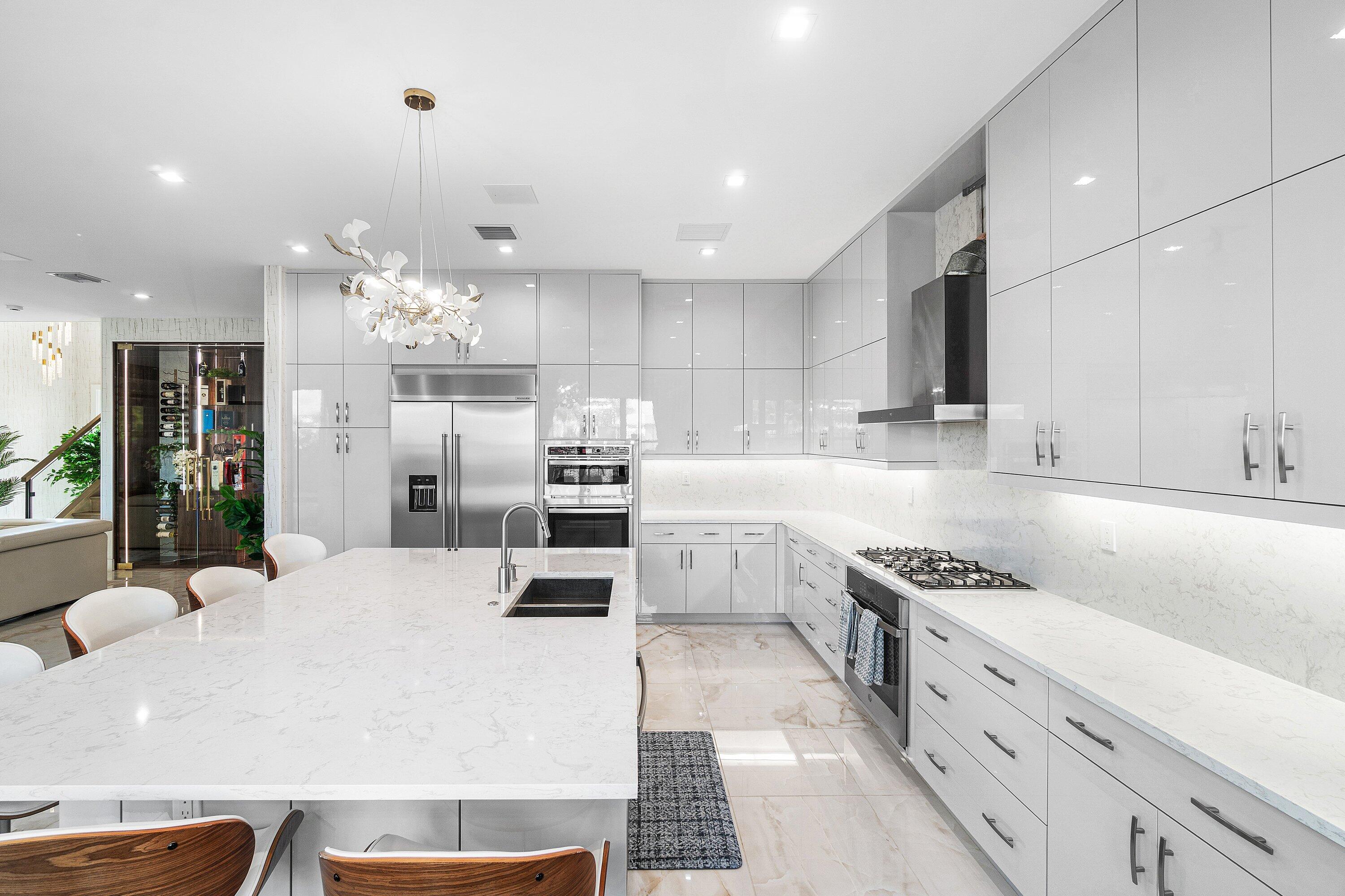 8233 Crystal Downs Avenue Boca Raton, FL 33434 - Photo 13 of 58 a kitchen with stainless steel appliances kitchen island granite countertop a stove a sink a refrigerator and white cabinets with wooden floor