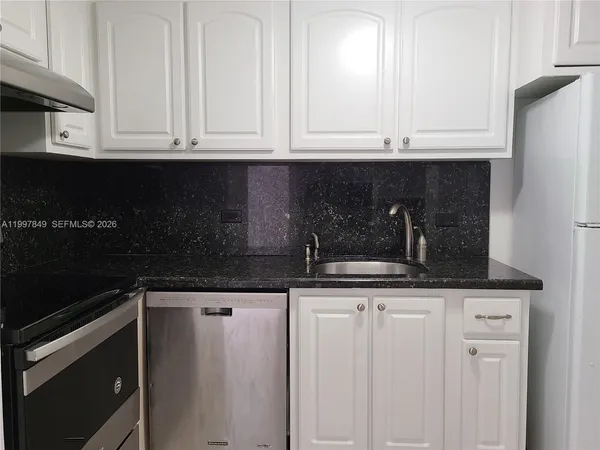 a kitchen with granite countertop white cabinets and black appliances