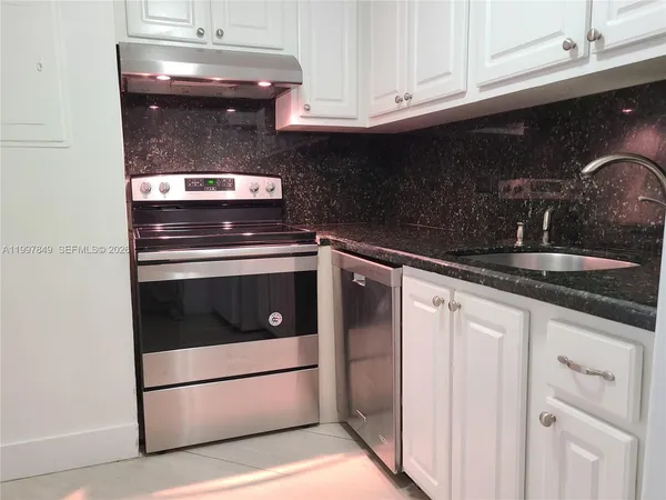 a kitchen with granite countertop white cabinets and white appliances