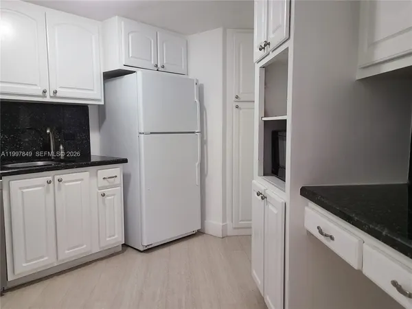 a kitchen with white cabinets and refrigerator