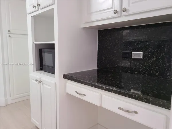 a hallway with granite countertop white cabinets and a fireplace