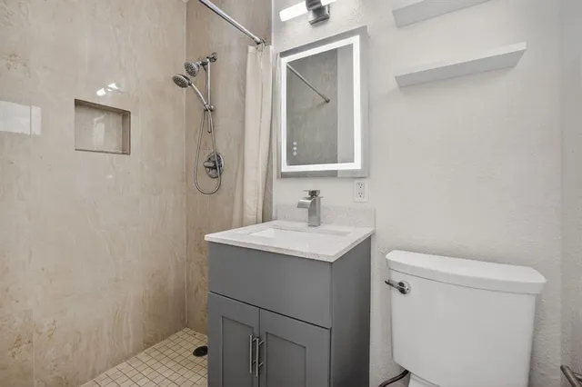 a bathroom with a granite countertop sink a toilet and shower
