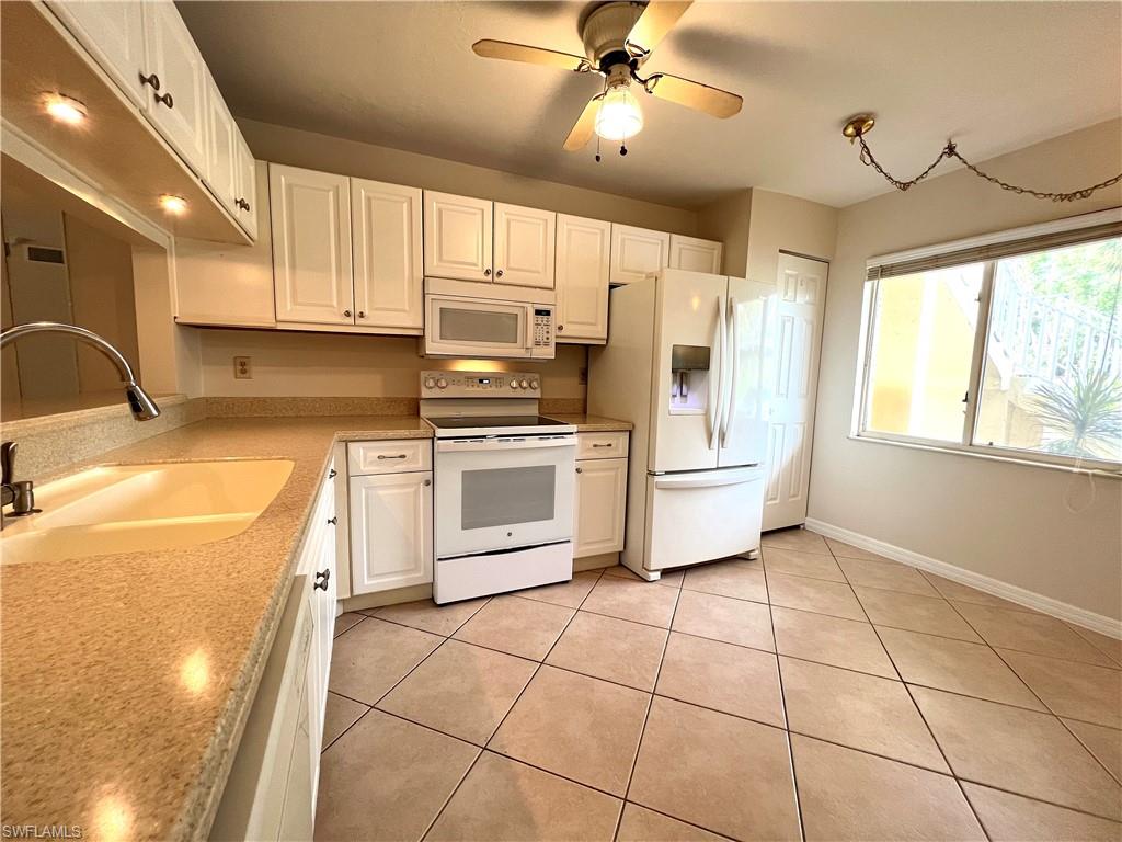 3471 County Barn Road, Unit F102 Naples, FL 34112 - Photo 4 of 19 a kitchen with a stove a refrigerator and white cabinets