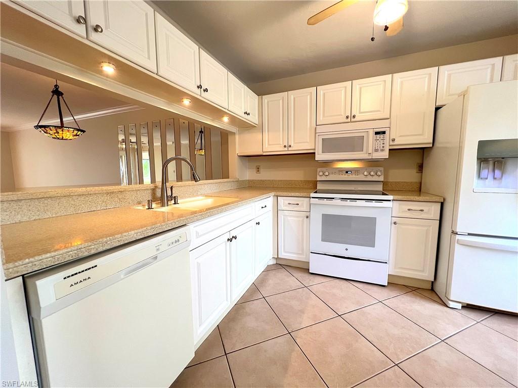 3471 County Barn Road, Unit F102 Naples, FL 34112 - Photo 5 of 19 a kitchen with white cabinets appliances and a sink