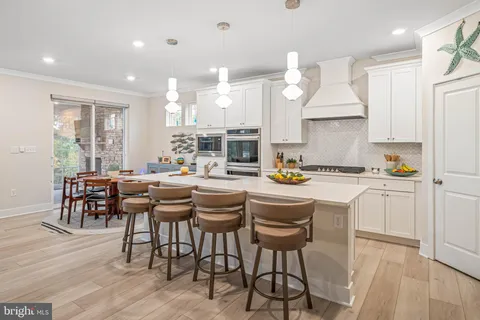 a kitchen with stainless steel appliances kitchen island granite countertop a table chairs sink and cabinets