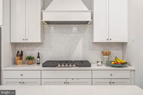 a kitchen with white cabinets and a stove with wooden floor