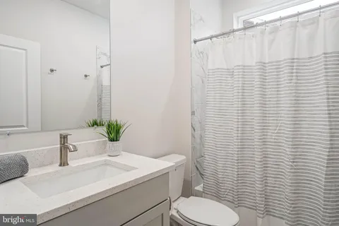 a bathroom with a sink a toilet a mirror and shower curtain