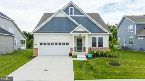 a view of a house with a big yard plants and large tree