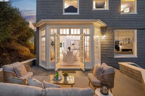 a view of a brick house with couches chairs and table in front of house