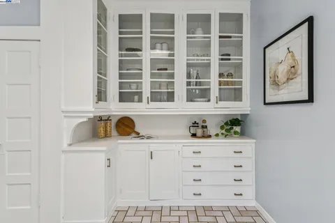 a large white kitchen with granite countertop a stove a sink a window and white cabinets