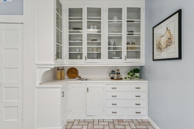 a large white kitchen with granite countertop a stove a sink a window and white cabinets