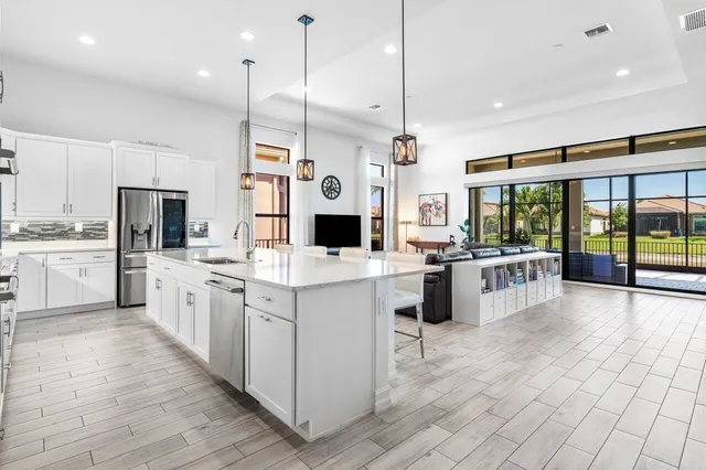a large white kitchen with a large window and stainless steel appliances