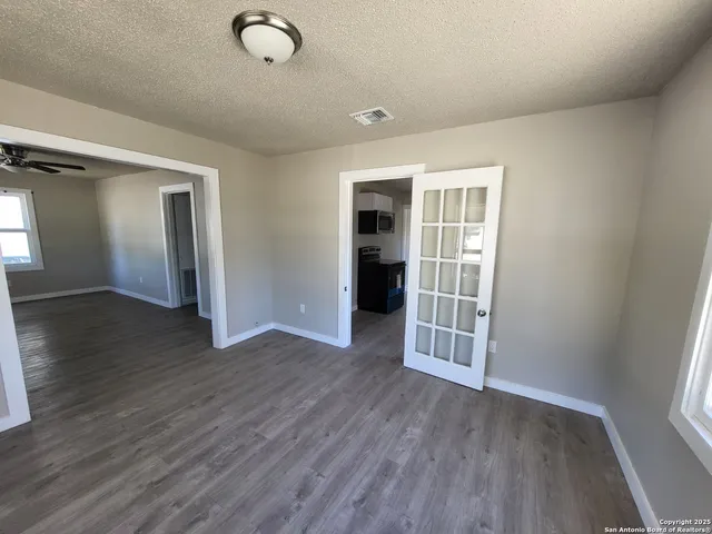 an empty room with wooden floor and windows