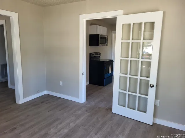 a view of an empty room with wooden floor and a window