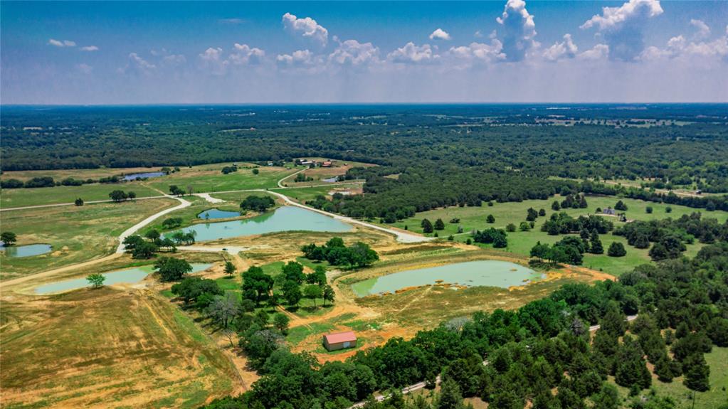 1789 Brumelow Road Whitesboro, TX 76273 - Photo 7 of 30 Expansive rural landscape featuring multiple ponds, scattered trees, and a distant red-roofed structure