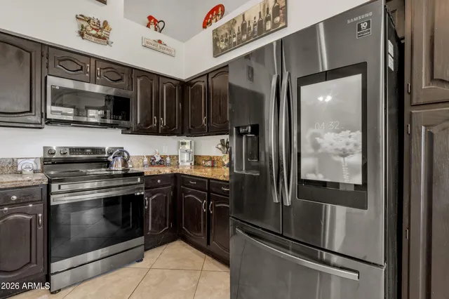 a dining hall with stainless steel appliances granite countertop a refrigerator a table and chairs