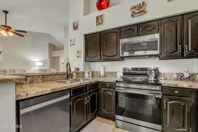 a kitchen with stainless steel appliances granite countertop a refrigerator a stove and a sink with wooden floor