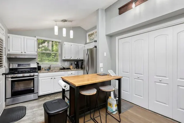 a kitchen with granite countertop white cabinets and stainless steel appliances