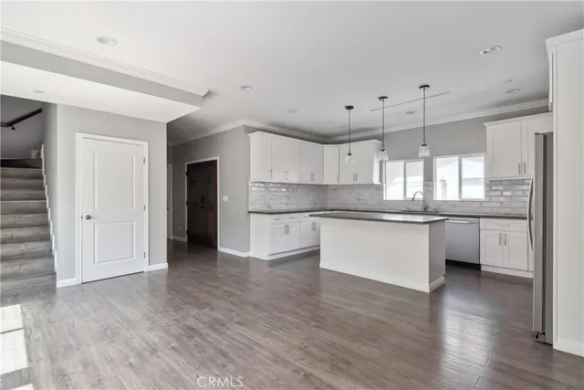 a large kitchen with white cabinets and wooden floor