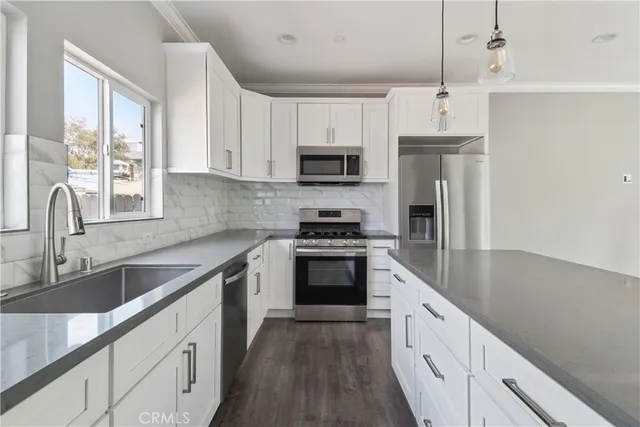 a kitchen with granite countertop a sink a counter space stainless steel appliances and cabinets
