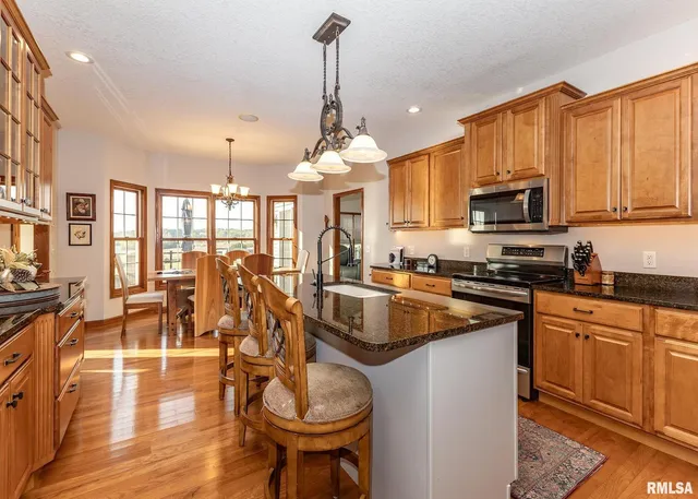 a kitchen with stainless steel appliances granite countertop a kitchen island a stove and a sink