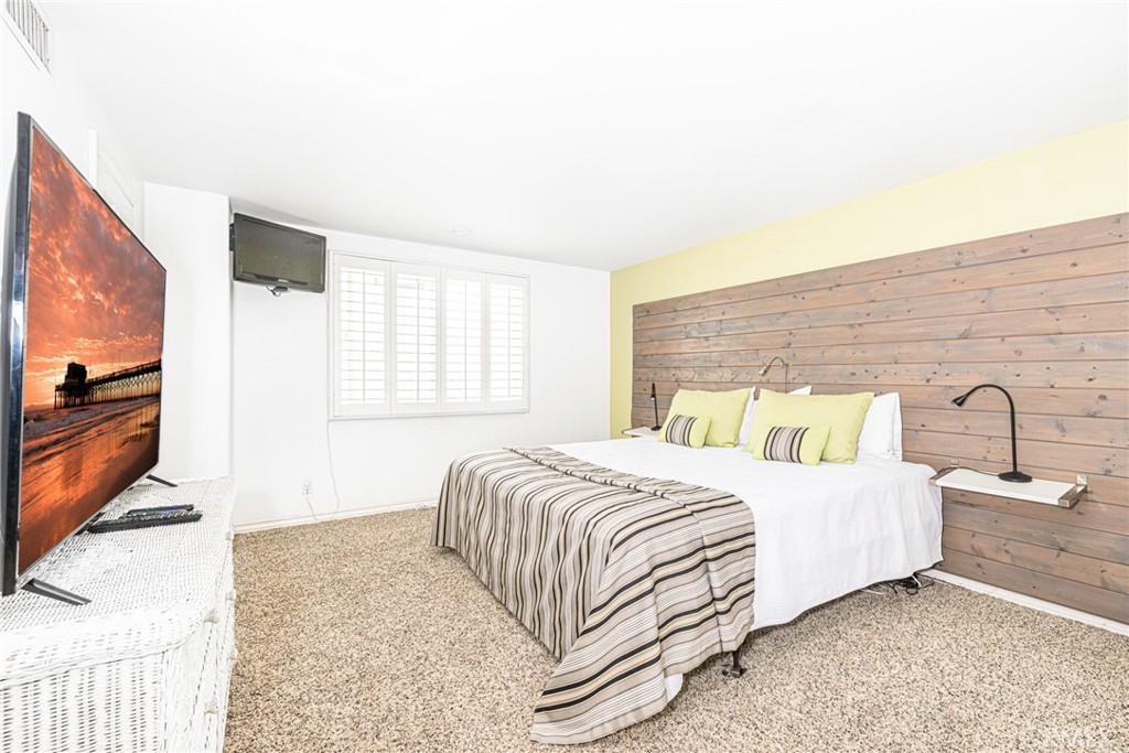 1720 West Oceanfront, Unit B Newport Beach, CA 92663 - Photo 14 of 28 a bedroom with a large bed and a flat tv screen on dresser