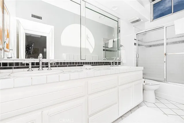 a bathroom with a double vanity sink toilet and a mirror