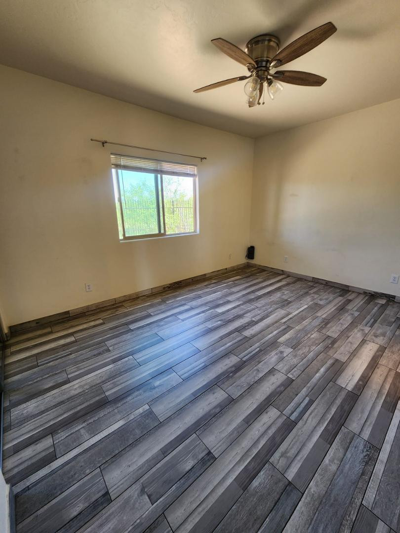 3641 Camino Del Rancho Douglas, AZ 85607 - Photo 6 of 20 an empty room with wooden floor chandelier fan and windows