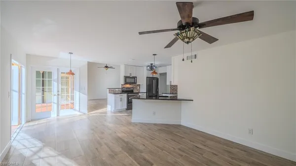 a kitchen with stainless steel appliances a dining table chairs and wooden floor