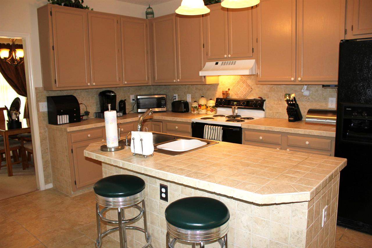5316 Bentgrass Drive Raleigh, NC 27610 - Photo 9 of 25 Please note the center island with breakfast bar seating. The attractive cabinets are highlighted by the tile countertops.