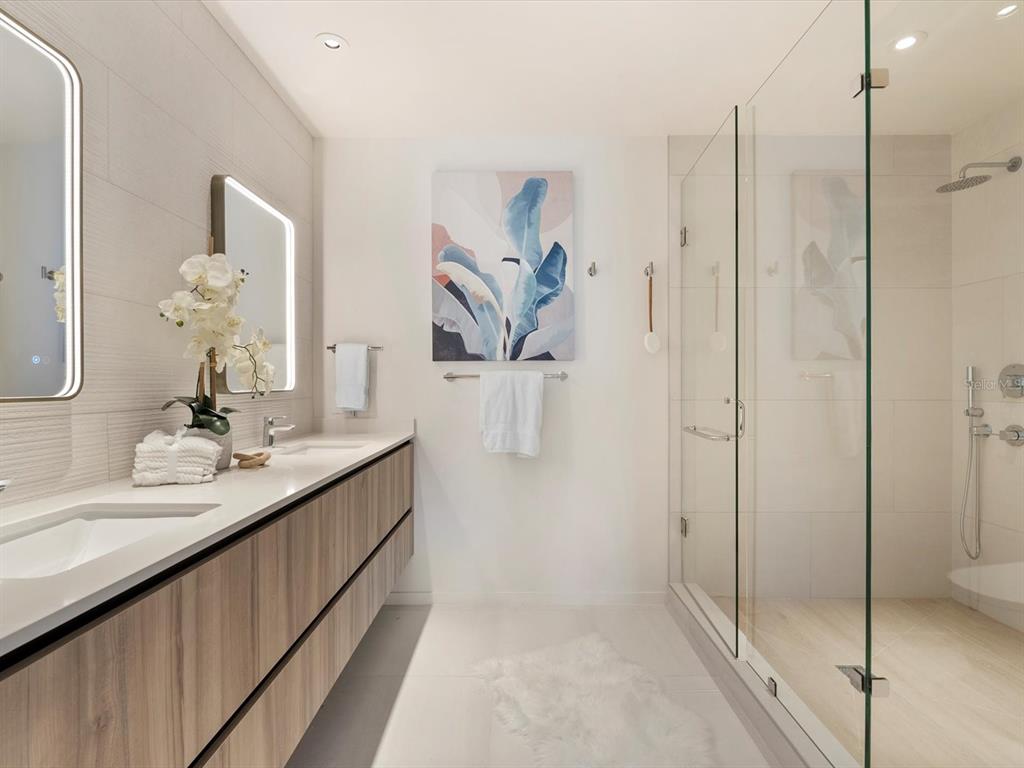 1020 Sunset Point Road, Unit 605 Clearwater, FL 33755 - Photo 12 of 35 a en suite bathroom with a double vanity sink mirror and shower