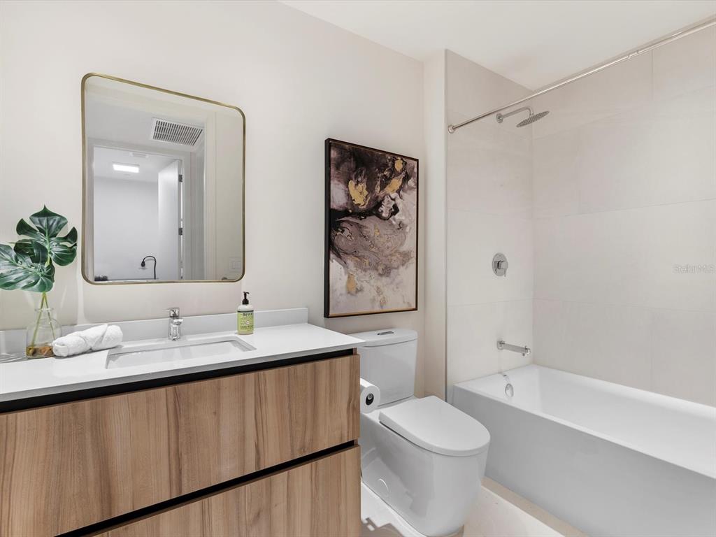 1020 Sunset Point Road, Unit 605 Clearwater, FL 33755 - Photo 16 of 35 a bathroom with a granite countertop sink toilet a large mirror a shower and a bathtub