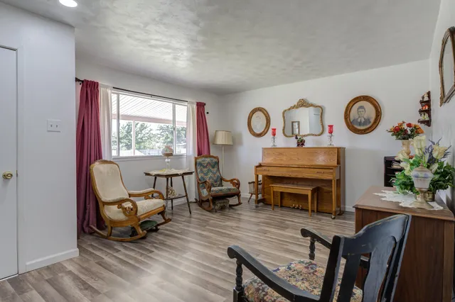 a living room with furniture a clock on wall and a window