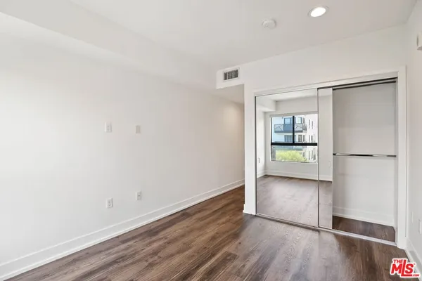 an empty room with wooden floor a ceiling fan and windows