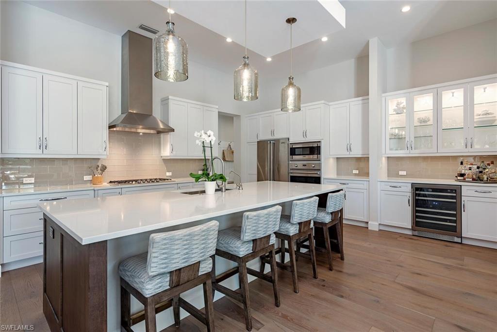 16715 Enclave Circle Naples, FL 34110 - Photo 14 of 33 a kitchen with stainless steel appliances kitchen island granite countertop a table chairs sink and cabinets