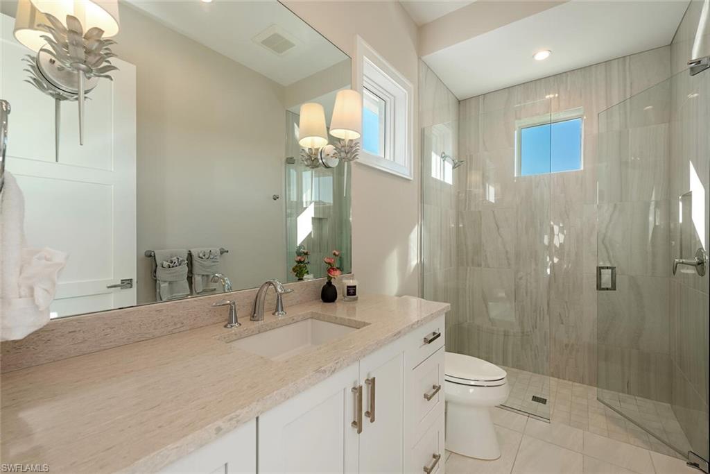 16715 Enclave Circle Naples, FL 34110 - Photo 26 of 33 a bathroom with a granite countertop sink a toilet and shower