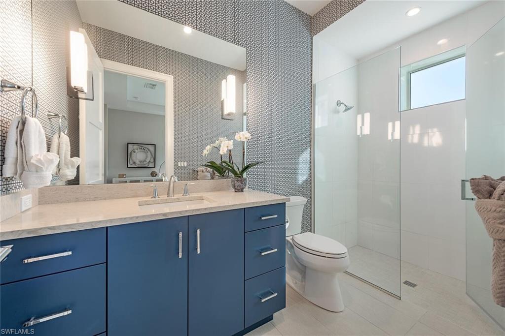 16715 Enclave Circle Naples, FL 34110 - Photo 28 of 33 a bathroom with a granite countertop sink a toilet and a mirror
