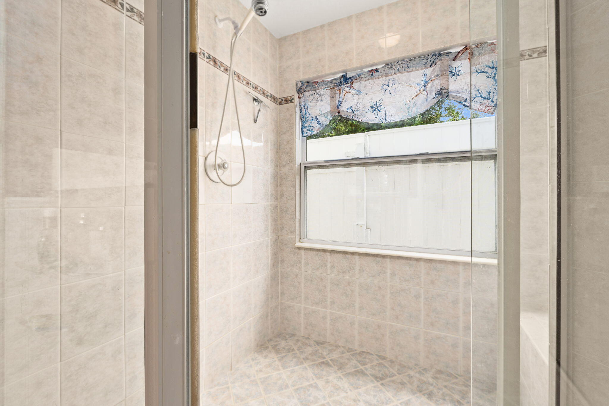 8964 Southeast Sunfish Place Hobe Sound, FL 33455 - Photo 34 of 51 a bathroom with a glass shower door and a window