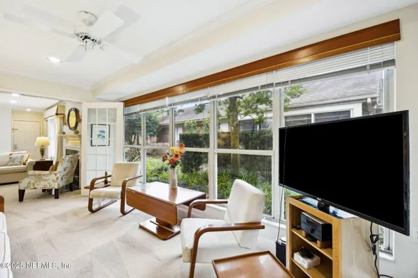 a living room with furniture a flat screen tv and floor to ceiling window