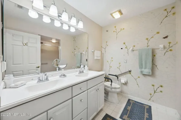 a bathroom with a double vanity sink mirror and toilet