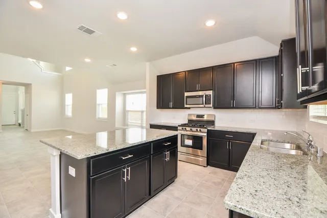a kitchen with stainless steel appliances granite countertop a sink stove and microwave